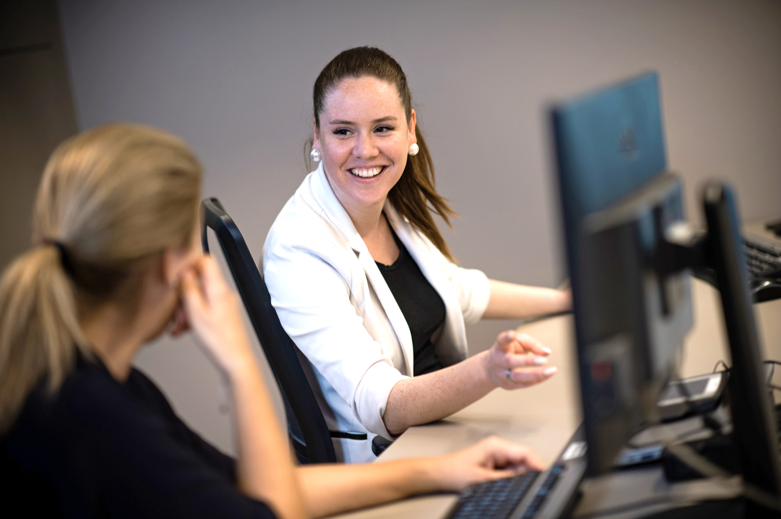 Zwei Frauen sitzen am Computer und unterhalten sich